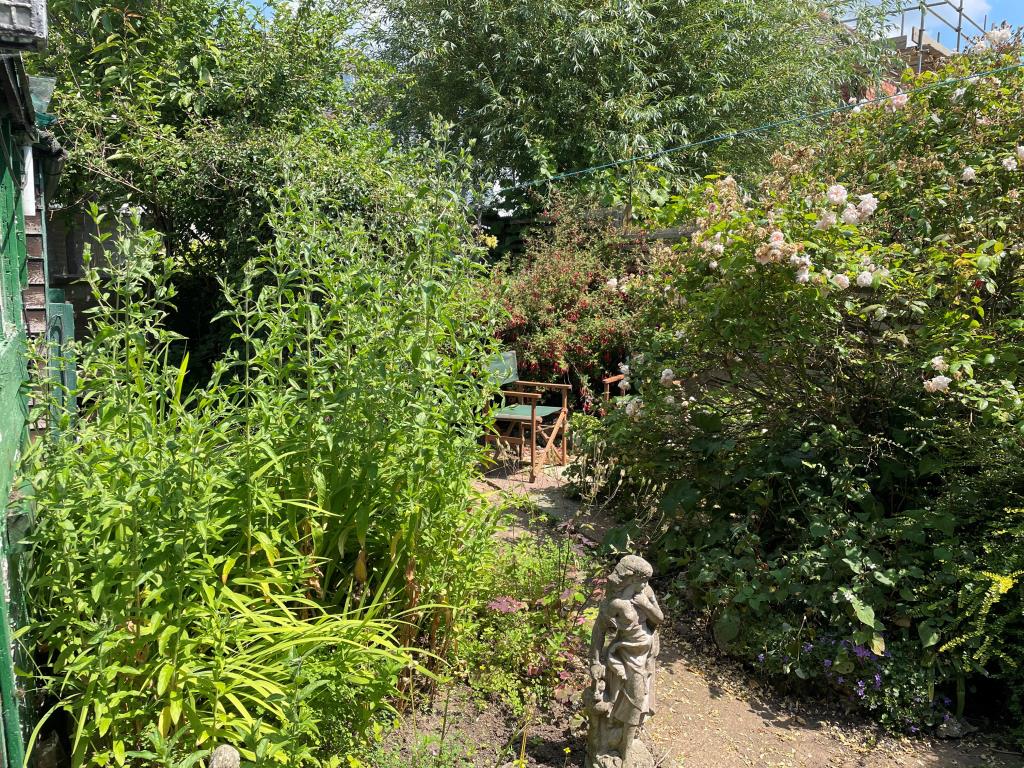 Lot: 19 - HOUSE IN NEED OF REFURBISHMENT AND REPAIR - Garden from ground floor with patio and flower borders